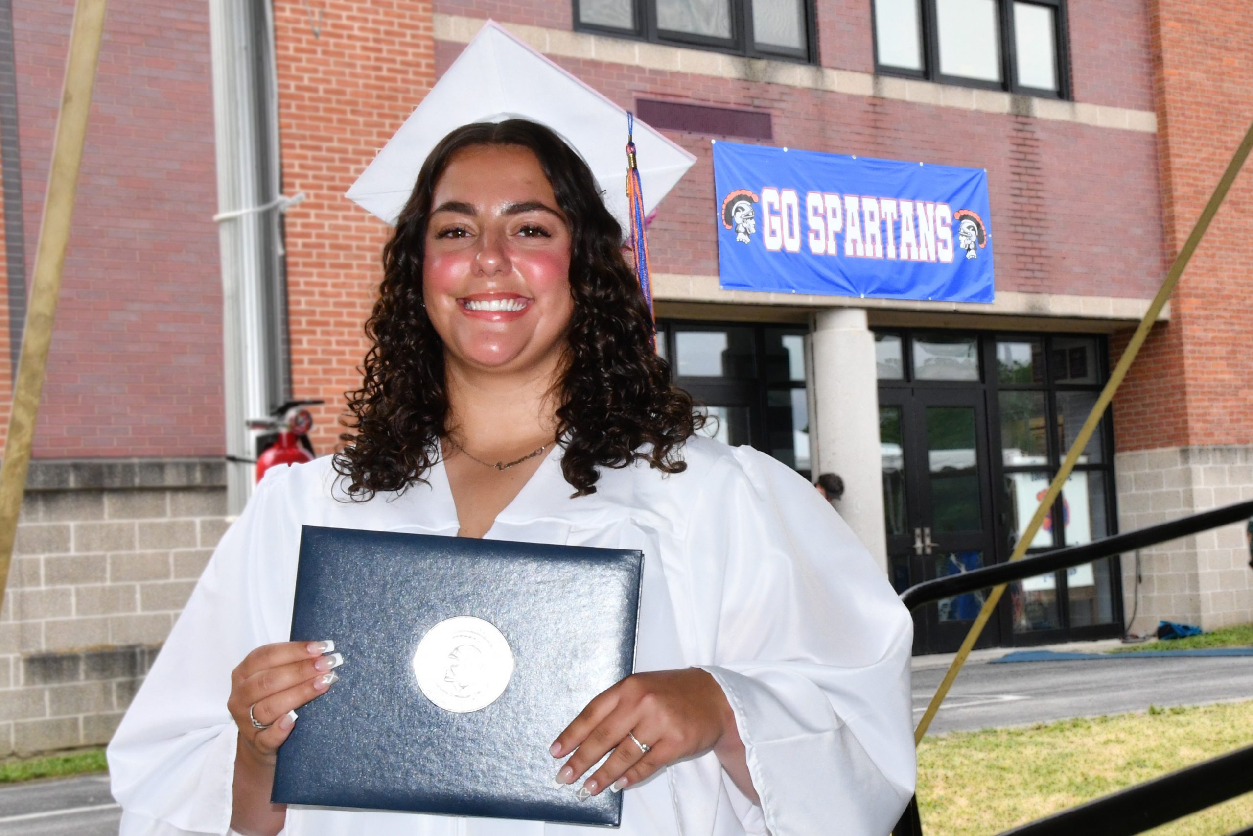 student smiles with diploma