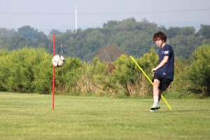 student kicks soccer ball at tryouts