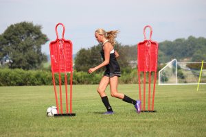 student weaves through obstacles on her way to the goal during tryouts