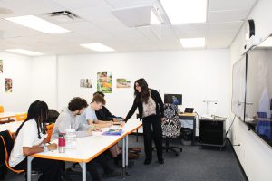 teacher points to student's paper in distance learning classroom