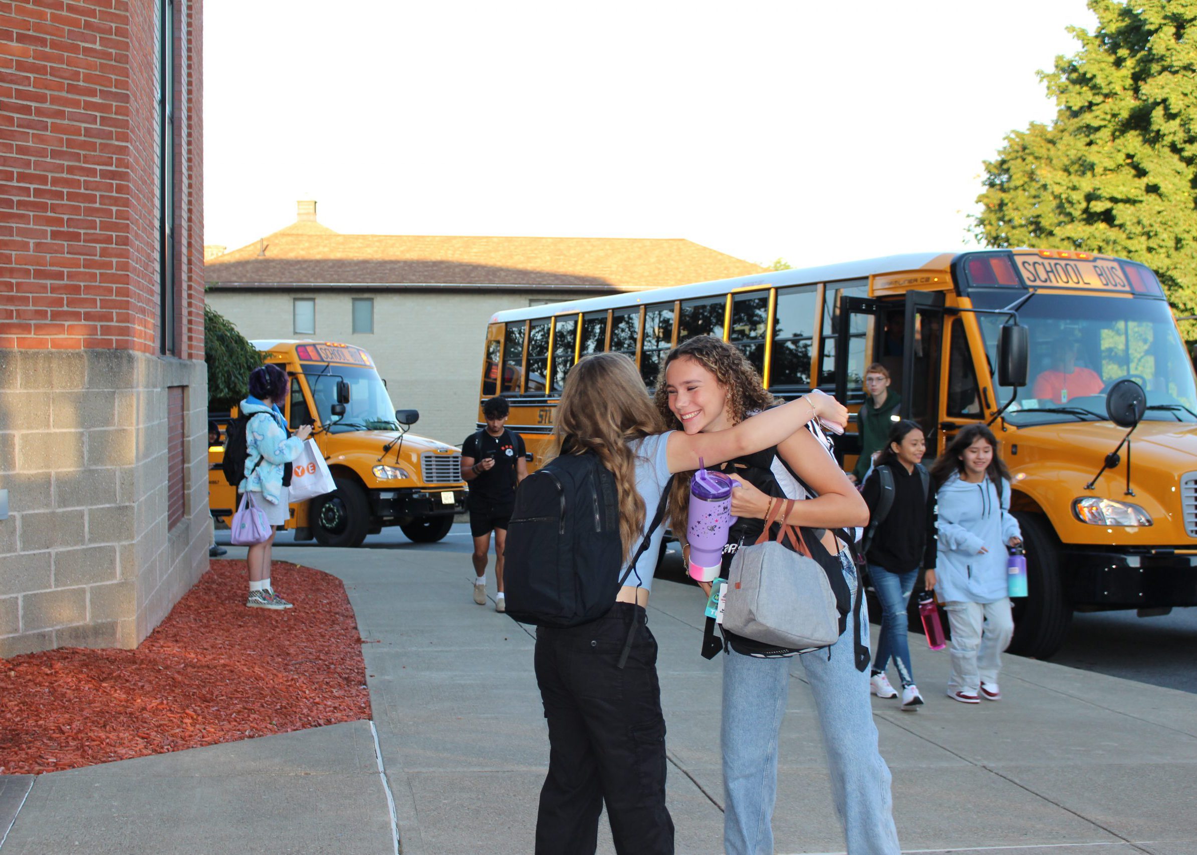 students hug as they walk in on the first day of school