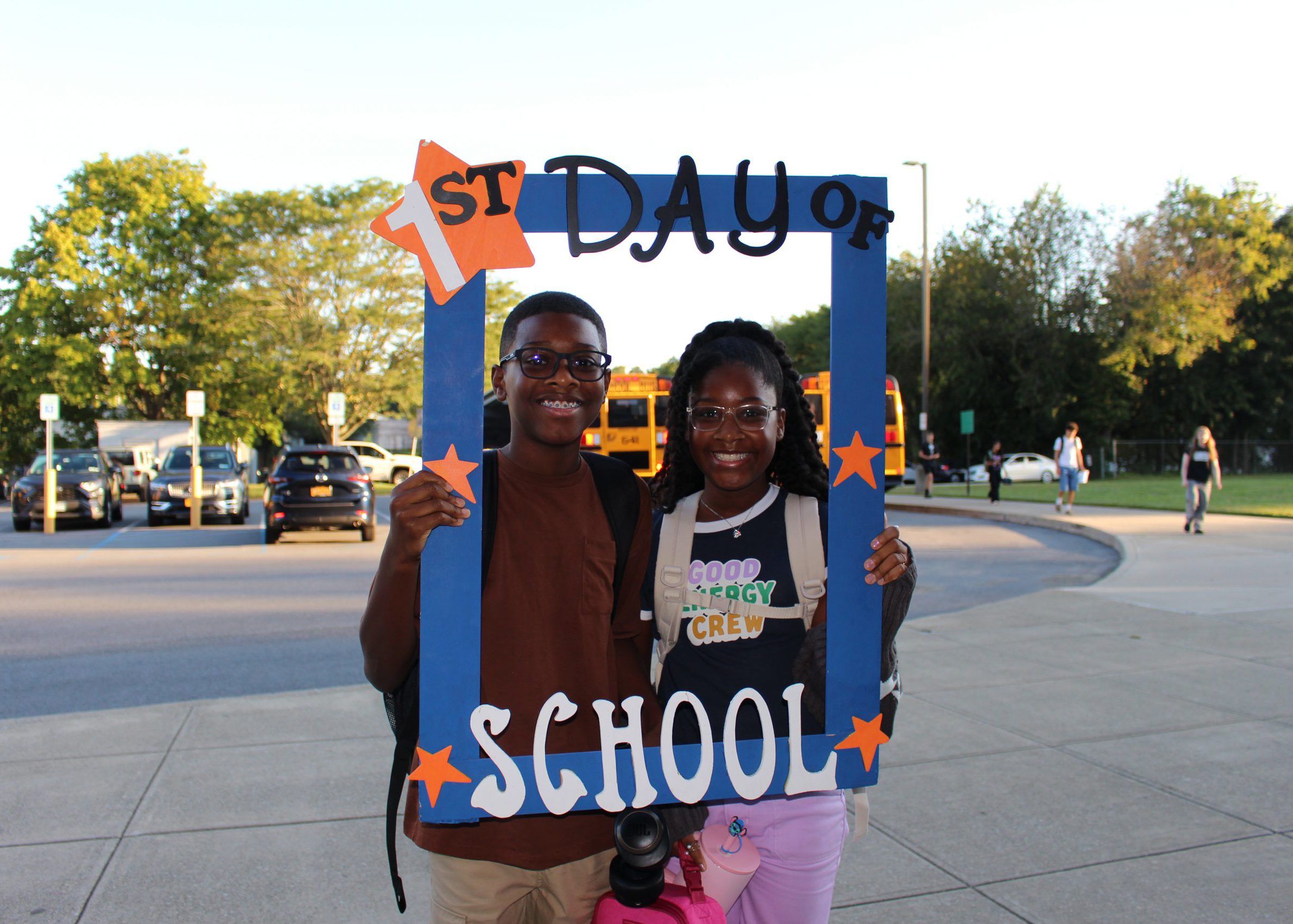 students smile from inside large frame that says "first day of school"