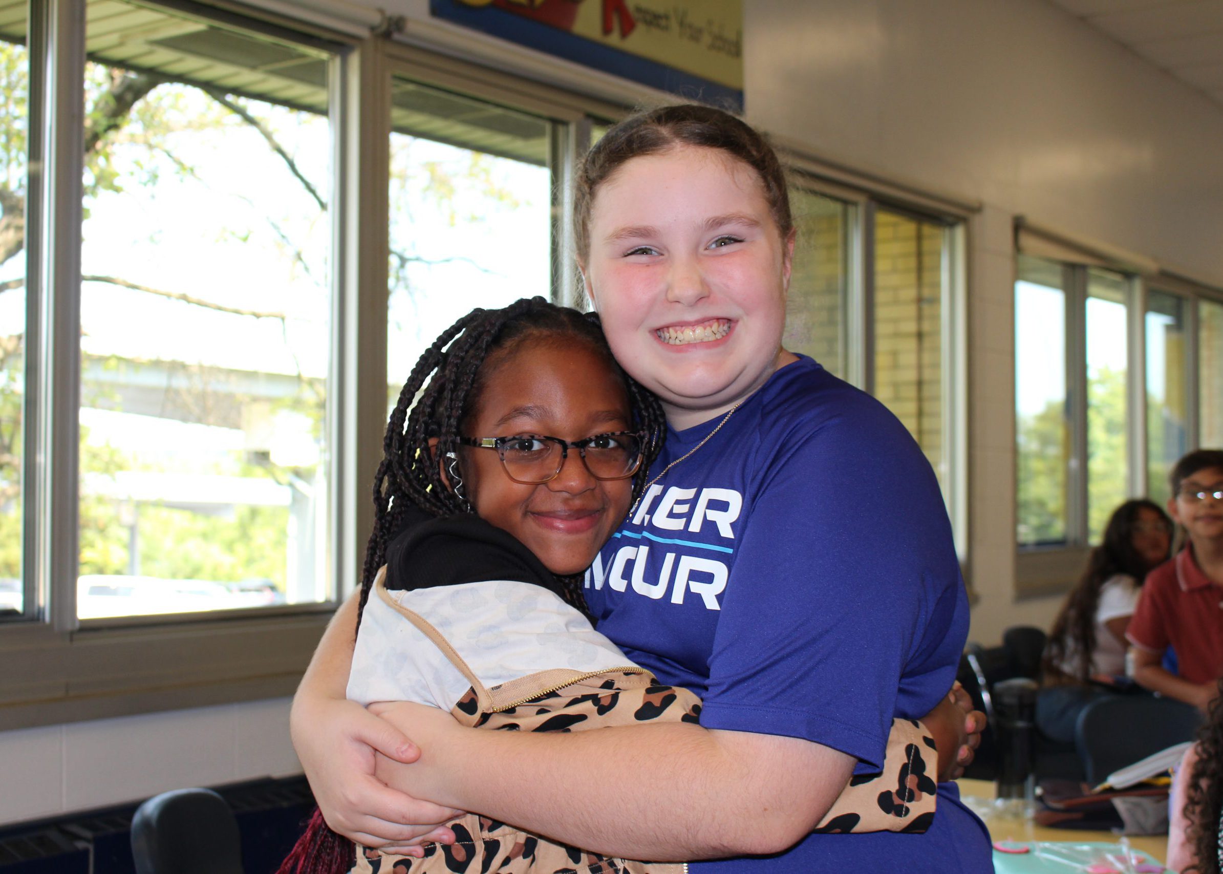 two students hug and smile at lunch