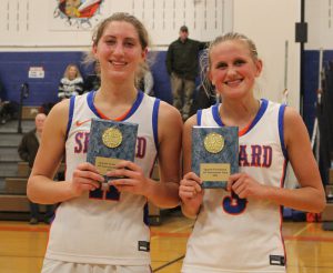 Two girls basketball players pose with plaques from the Spartan Invitational for making the All-Tournament team