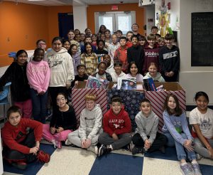 The whole 5th grade class pose for picture with toys they collected