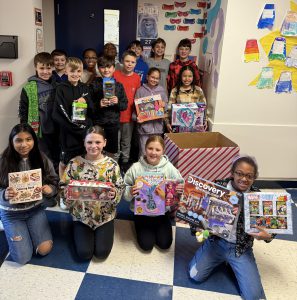 5th grade class pose for picture with toys they collected