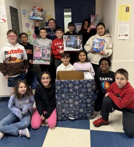 5th grade class pose for picture with toys they collected