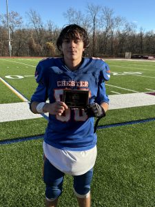 Student in blue football uniform holding plaque for Defensive MVP