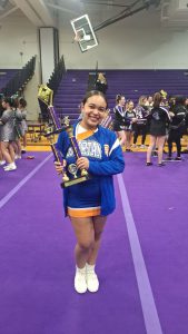 Cheer student posing for photo with trophy