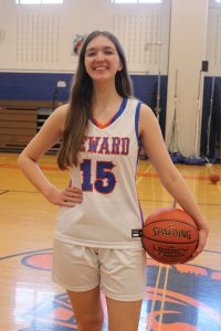 Student athlete poses in white uniform with basketball