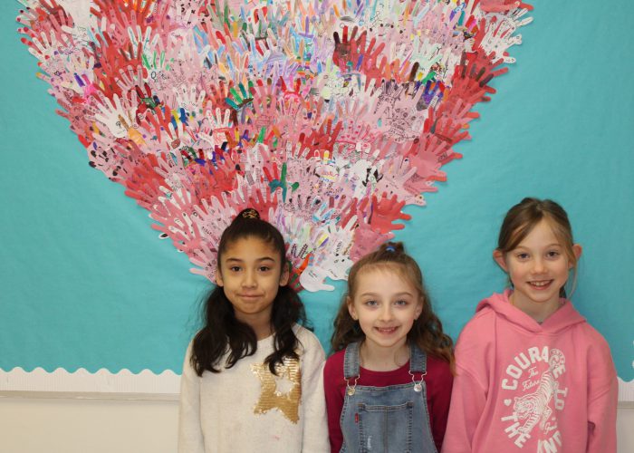 Students pose in front of school wide artwork