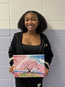 Student wearing black holding artwork