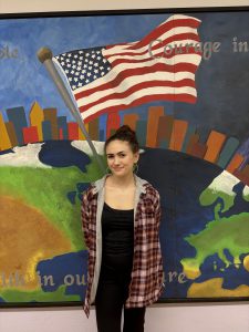 Student posing in front of mural