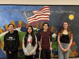 Students pose in front of mural